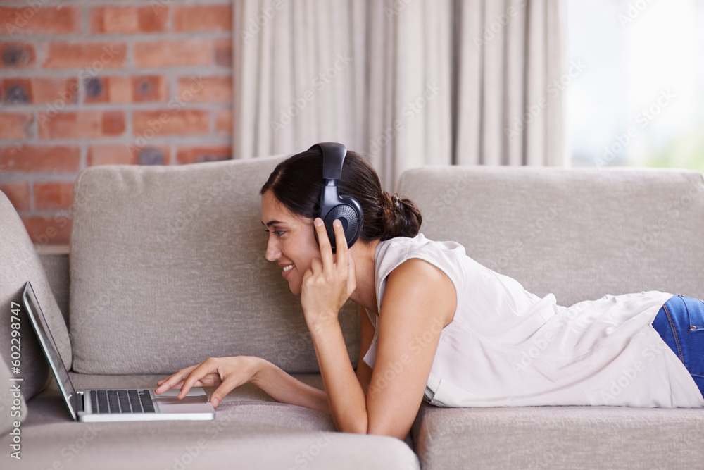 Woman, laptop and lying on couch with headphones for streaming, music and search for web video in home. Girl, smile and scrolling for movie, podcast or meme on internet to relax on sofa with computer Woman, laptop and lying on couch with headphones for streaming, music and search for web video in home. Girl, smile and scrolling for movie, podcast or meme on internet to relax on sofa with computer
