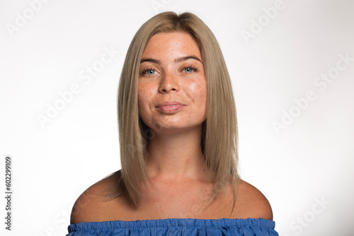 Beautiful girl with freckles with loose blond hair looks at the camera on a white background