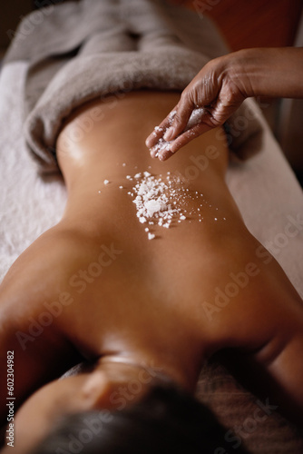 Salt sprinkle, back scrub and spa specialist hands with woman customer at a hotel with massage. Exfoliate therapy, luxury and relax treatment of a female person rest for skincare and wellness