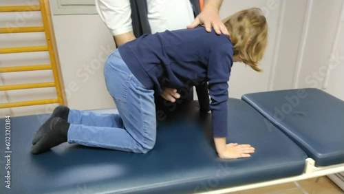 The cat is an exercise for the muscles of the back and the press. A 9-year-old girl trains under the guidance of a doctor - a physiotherapist. Therapy of juvenile and adolescent idiopathic scoliosis. photo