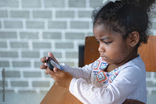 America African little girl are concentrating on the mobile phone in hands, children's addiction to mobile games concept