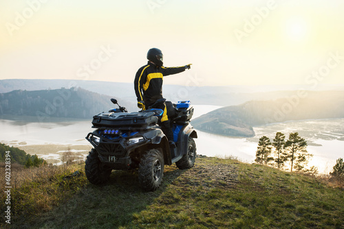 man standing near quad bike in the mountains at sunset.  freedom and travel adventure concept.