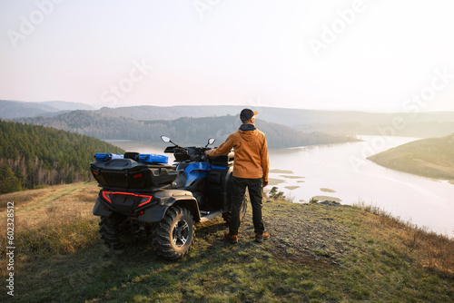 Back view of man traveler on a quad bike in the mountains at sunset. concept adventure summer vacations outdoor.