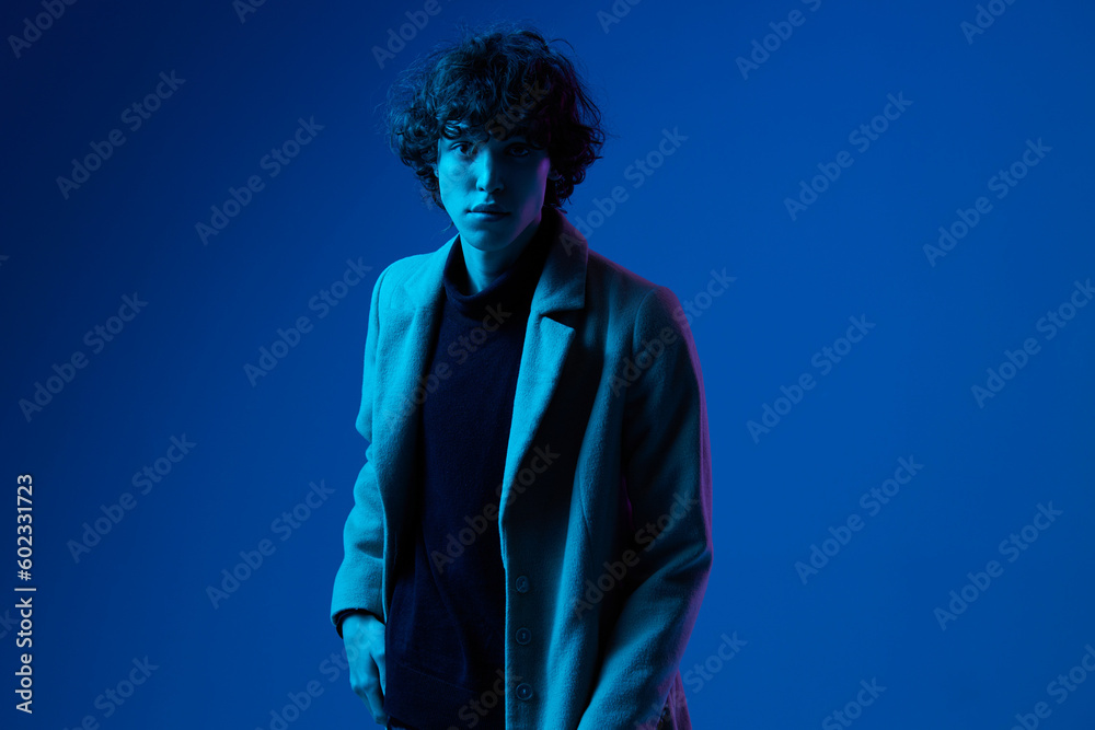 Man in fashion coat on dark blue background, neon light, style and trends, mixed light, men's fashion Man in fashion coat on dark blue background, neon light, style and trends, mixed light, men's fashion