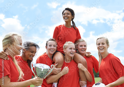 Trophy, winner and girl soccer team celebrating victory, achievement and match success on field. Football, prize and female teenage sports group lifting champion for celebration, competition or goal