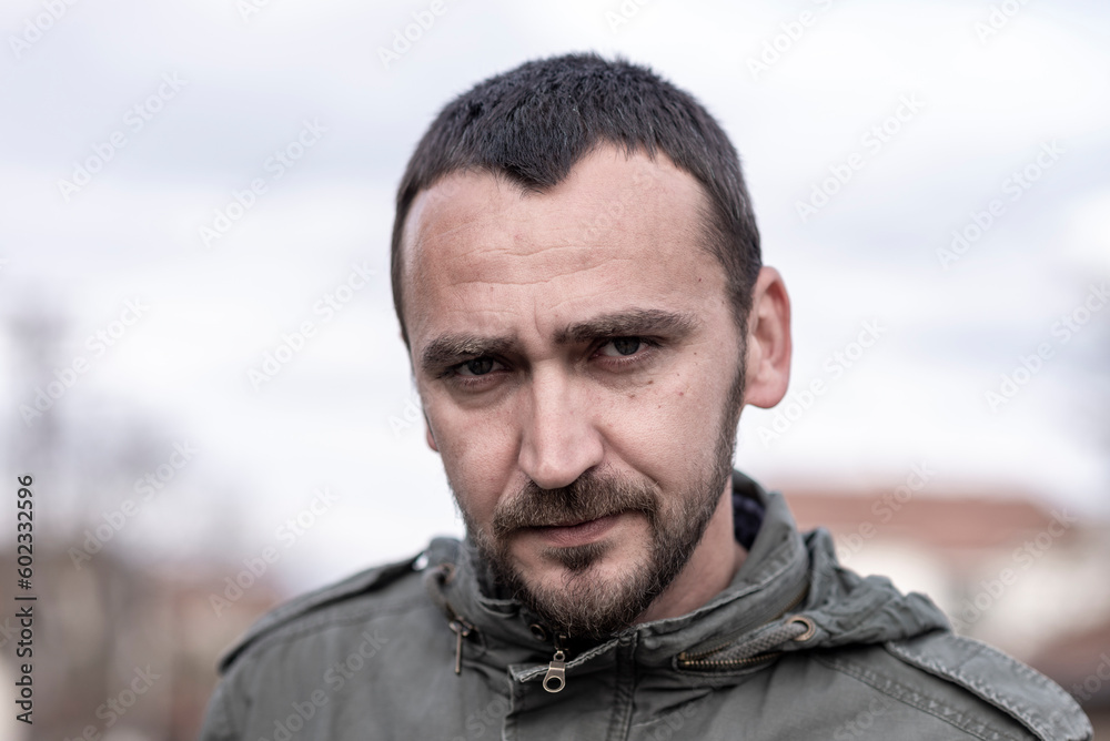 Portrait Of Young Handsome Caucasian Man with a stern or disappointed facial expression 
 looking directly at the camera