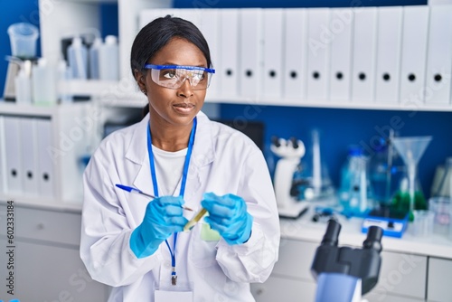 Young african american woman scientist writing on test tube at laboratory
