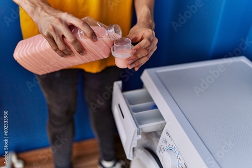 Young blond man pouring detergent at laundry room