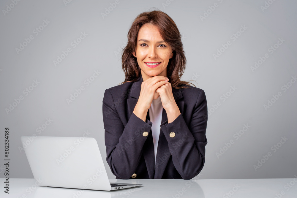 Studio portrait of an attractive mid aged woman with laptop sitting at isolated background Studio portrait of an attractive mid aged woman with laptop sitting at isolated background