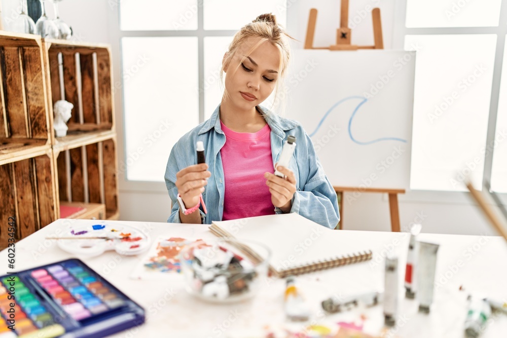 Young caucasian woman artist choosing color pen at art studio