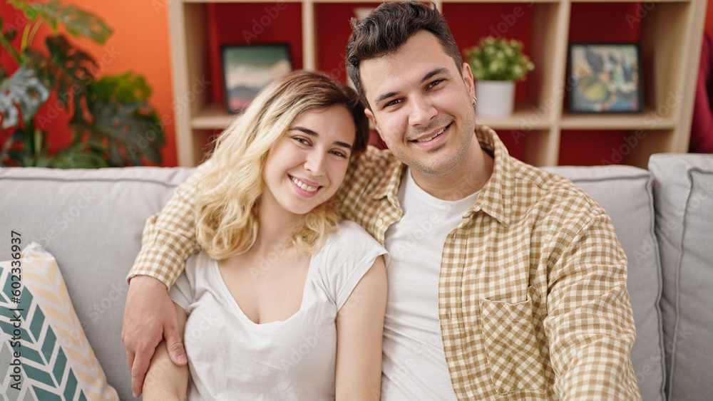 Man and woman couple hugging each other sitting on sofa at home Man and woman couple hugging each other sitting on sofa at home