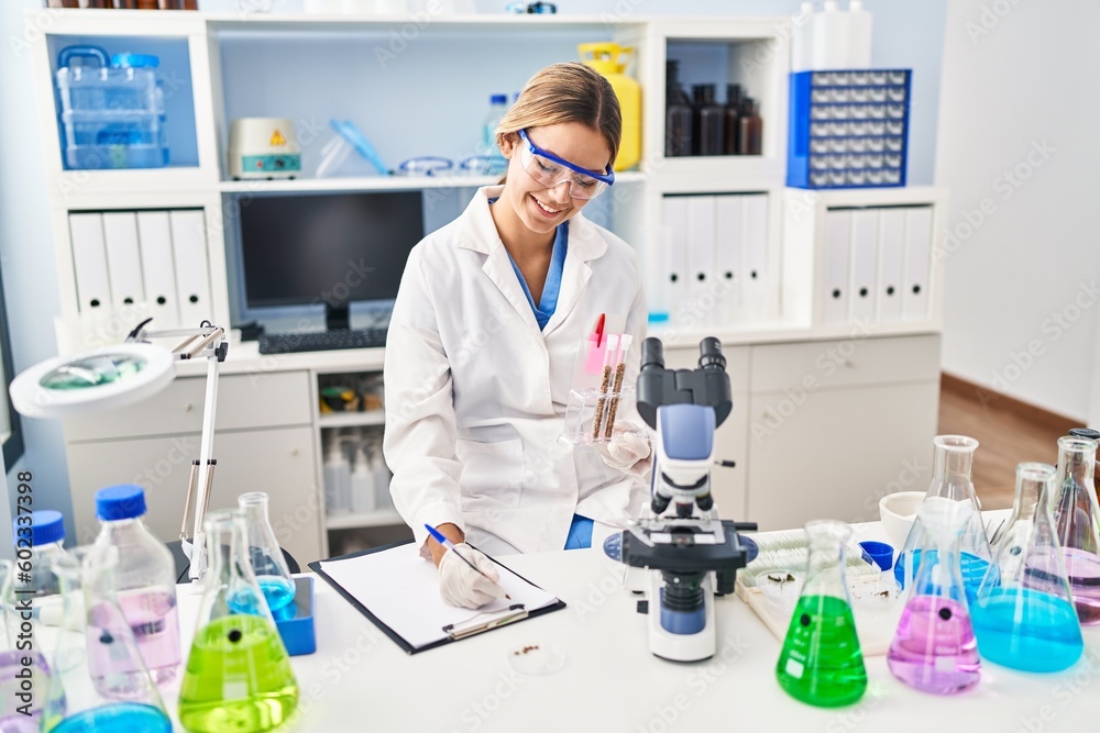 Young hispanic woman scientist write on document holding test tubes at laboratory Young hispanic woman scientist write on document holding test tubes at laboratory