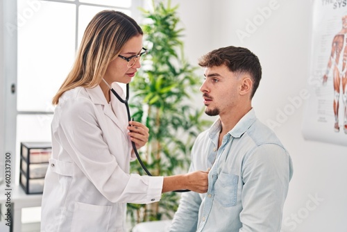 Young man and woman doctor and patient auscultating heart at clinic