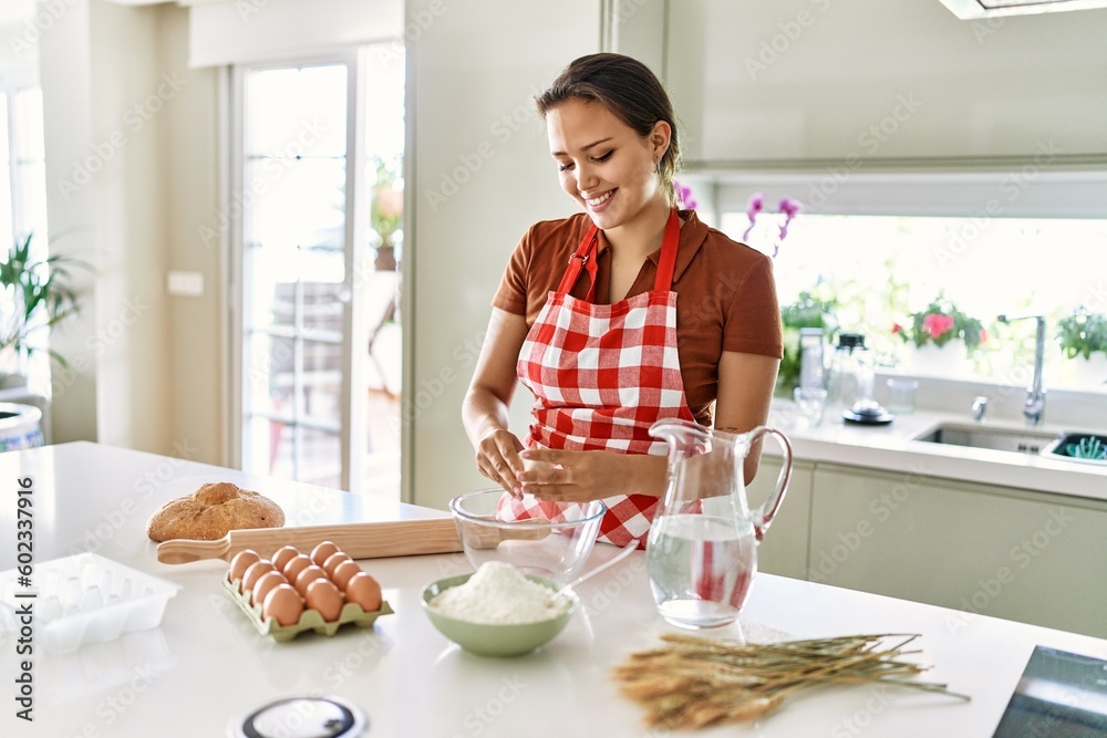 Young beautiful hispanic woman smiling confident mixing bread dough on bowl at the kitchen Young beautiful hispanic woman smiling confident mixing bread dough on bowl at the kitchen