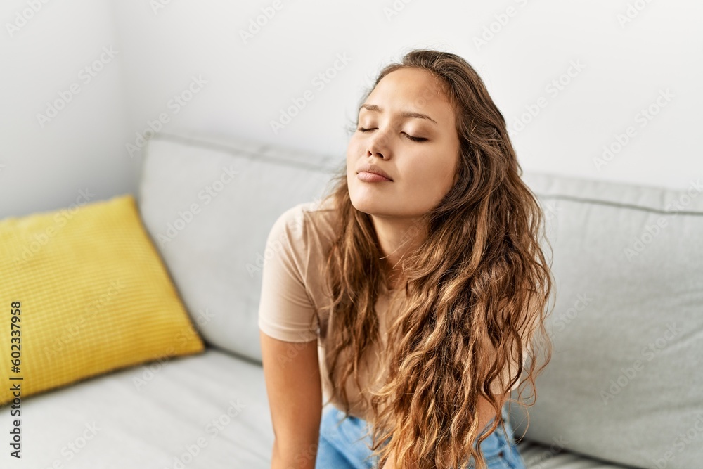 Young beautiful hispanic woman sitting on sofa breathing at home Young beautiful hispanic woman sitting on sofa breathing at home