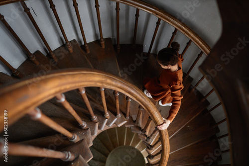 High angle view of little girl going up the wooden stairs