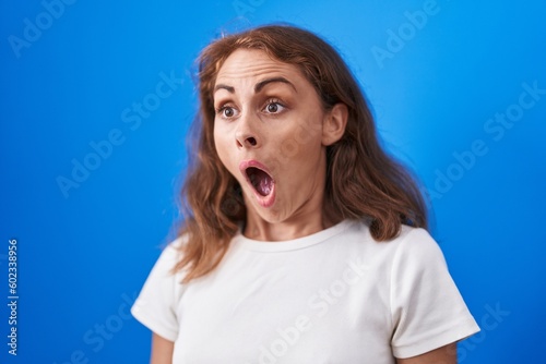 Young beautiful hispanic woman standing with surprise expression over isolated blue background