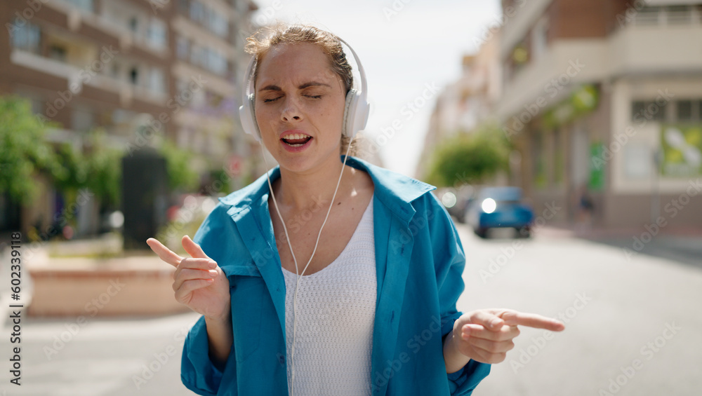 Young woman listening to music dancing at street