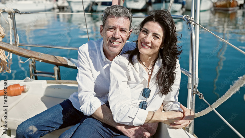 Senior man and woman couple hugging each other sitting together on boat at boat