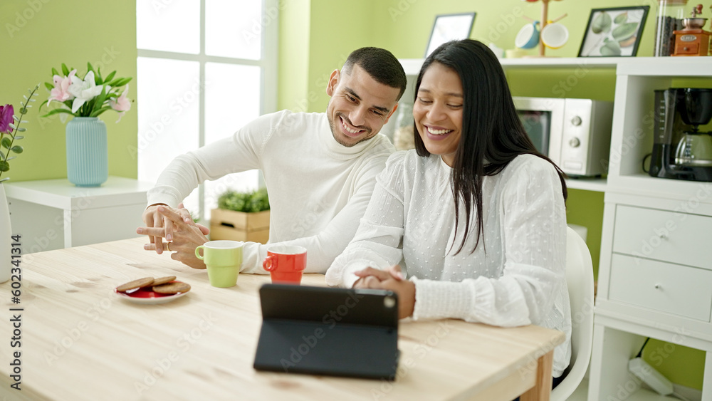 Man and woman couple having breakfast watching video on touchpad at home