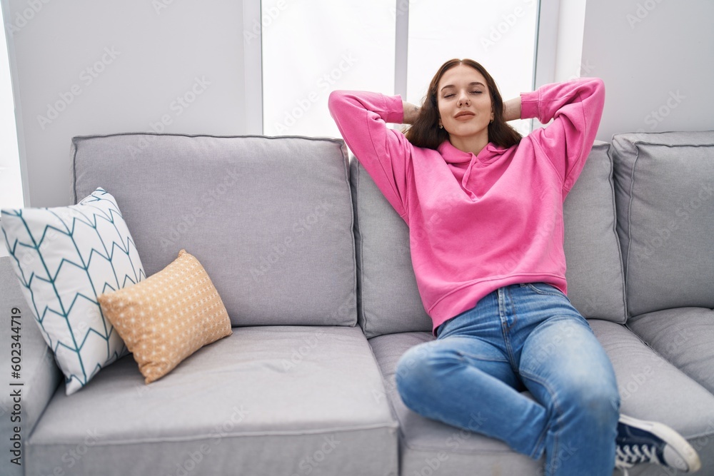 Young woman relaxed with hands on head sitting on sofa at home Young woman relaxed with hands on head sitting on sofa at home