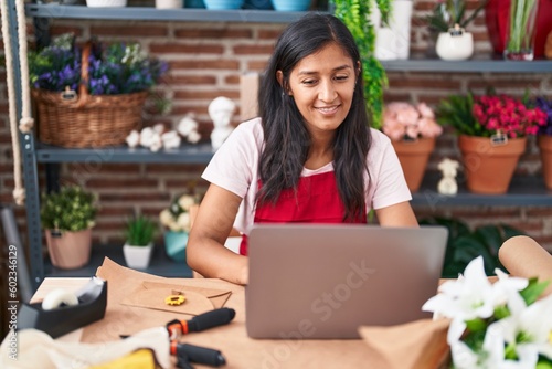 Young beautiful hispanic woman florist smiling confident using laptop at flower shop © Krakenimages.com