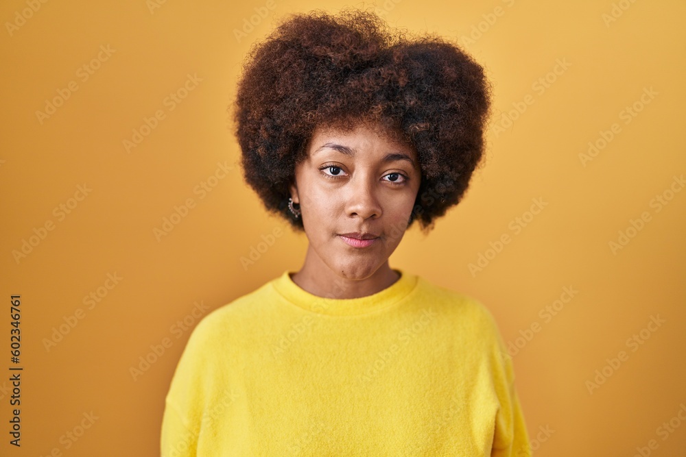 Young african american woman standing over yellow background relaxed with serious expression on face. simple and natural looking at the camera.