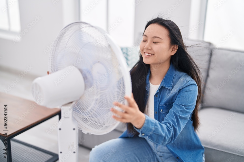 Young chinese woman using ventilator sitting on sofa at home Young chinese woman using ventilator sitting on sofa at home