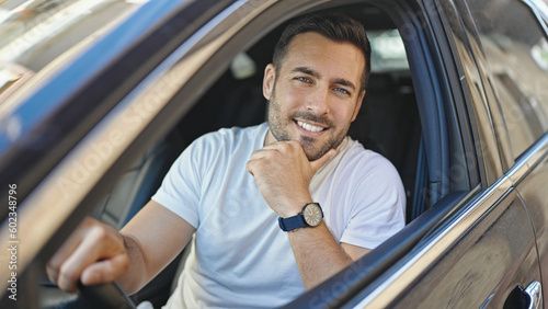Young hispanic man smiling confident sitting on car at street