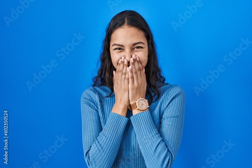 фотографія Young brazilian woman standing over blue isolated background laughing and embarr