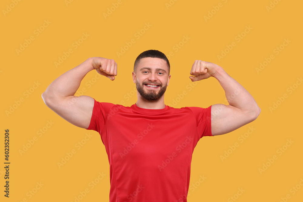 Portrait of handsome man showing muscles on yellow background Portrait of handsome man showing muscles on yellow background