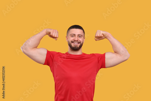 Portrait of handsome man showing muscles on yellow background © New Africa