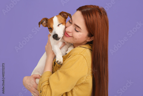 Woman hugging her cute Jack Russell Terrier dog on violet background © New Africa
