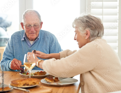 Love, help and senior couple eating lunch together in the dining room of their modern home. Happy, date and elderly man and woman in retirement talking, bonding and enjoying meal or food in a house.