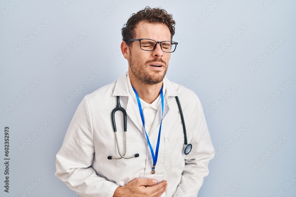 Young hispanic man wearing doctor uniform and stethoscope with hand on stomach because indigestion, painful illness feeling unwell. ache concept. Young hispanic man wearing doctor uniform and stethoscope with hand on stomach because indigestion, painful illness feeling unwell. ache concept.