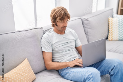 Young man using laptop sitting on sofa at home