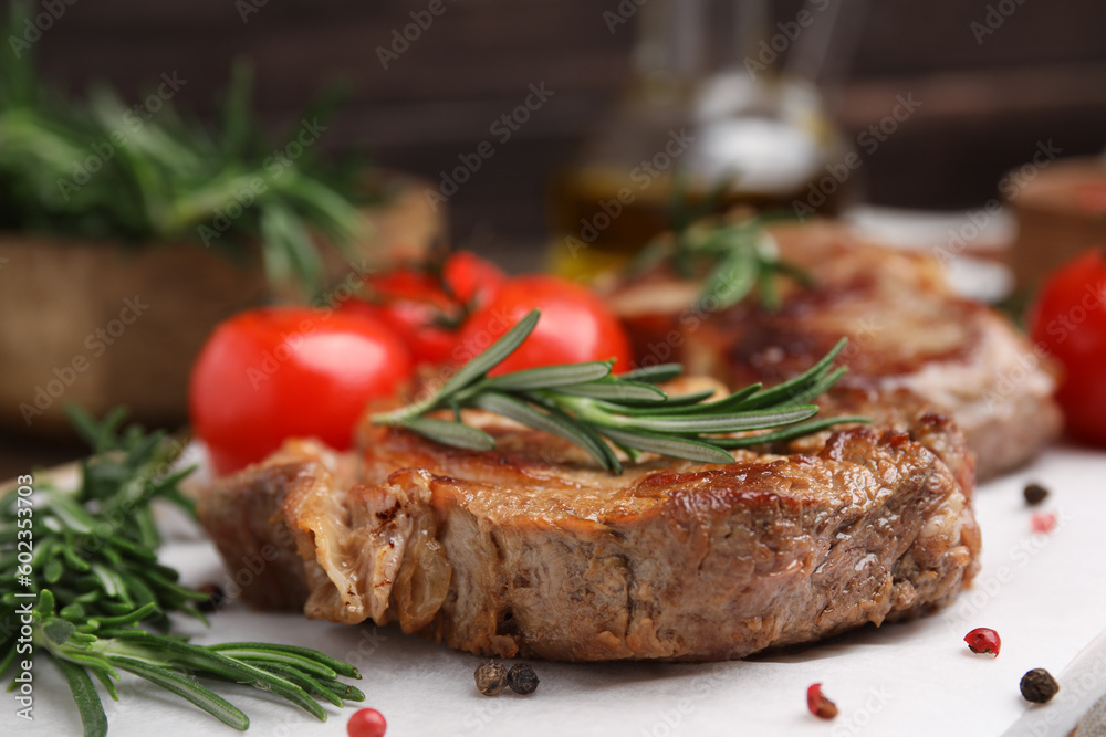 Delicious fried meat with rosemary, tomatoes and spices on white table, closeup