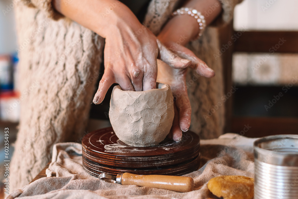 Fototapeta premium Female sculptor making clay mug in a home workshop,hands close-up.Small business,entrepreneurship,hobby, leisure concept.