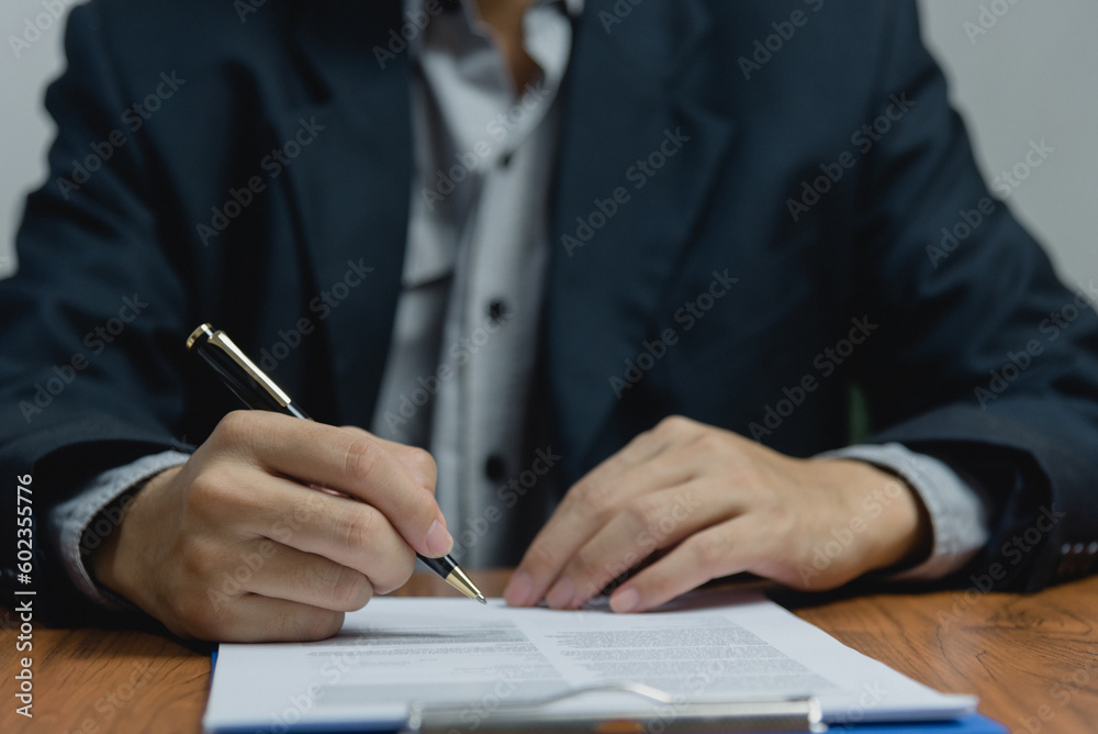 Businessman holding a pen signing a document, law ,job search, write a personal contract on desk. Businessman holding a pen signing a document, law ,job search, write a personal contract on desk.