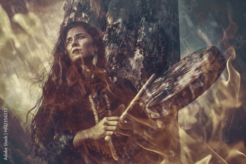 beautiful shamanic girl playing on shaman frame drum in the nature. Fire background. © jozefklopacka