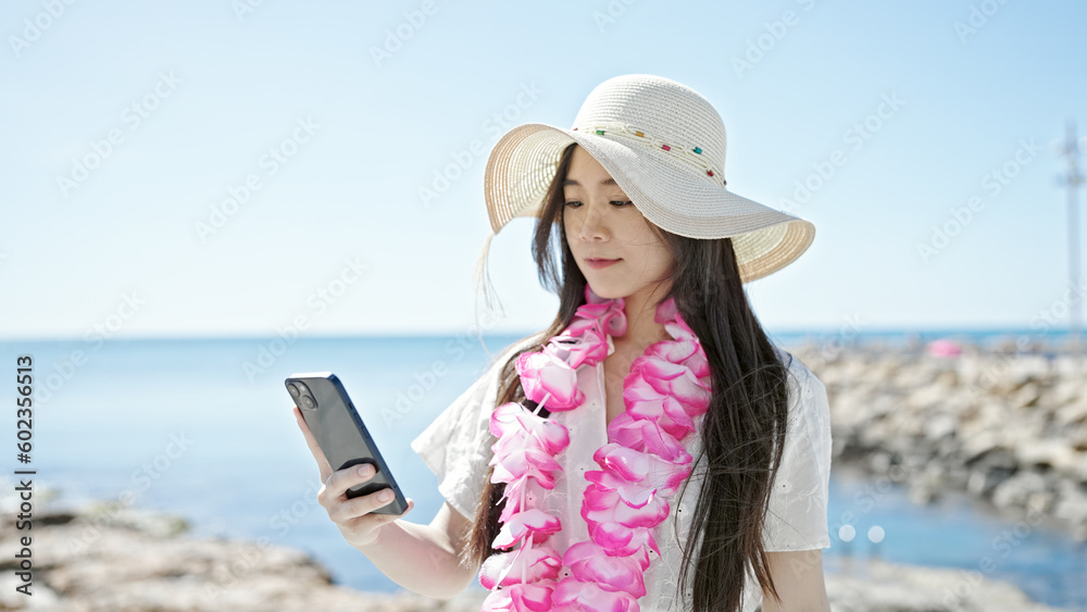 Fototapeta premium Young chinese woman tourist using smartphone at seaside