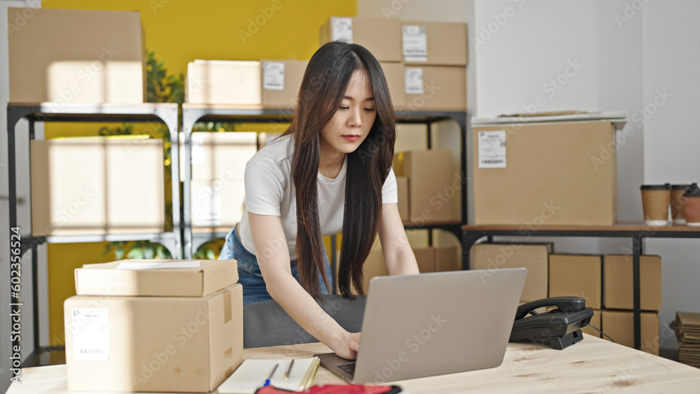 Young chinese woman ecommerce business worker using laptop standing at office Young chinese woman ecommerce business worker using laptop standing at office