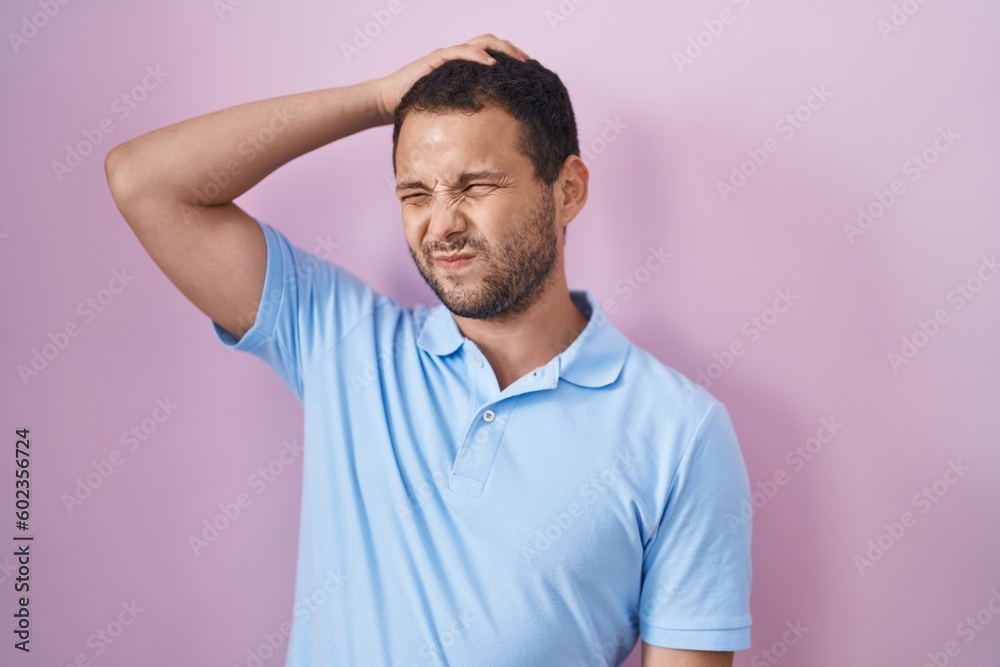 Hispanic man standing over pink background confuse and wondering about question. uncertain with doubt, thinking with hand on head. pensive concept. Hispanic man standing over pink background confuse and wondering about question. uncertain with doubt, thinking with hand on head. pensive concept.