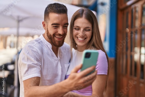 Man and woman couple smiling confident using smartphone at street