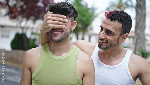 Two men couple smiling confident covering eyes with hand at street