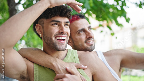 Two men couple smiling confident hugging each other at park