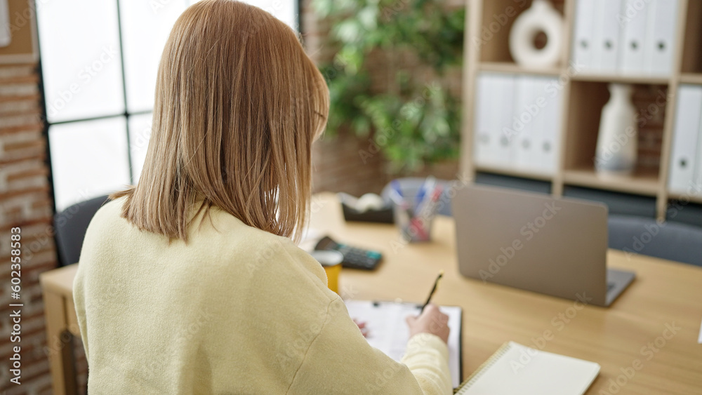 Young blonde woman business worker writing on document at office Young blonde woman business worker writing on document at office