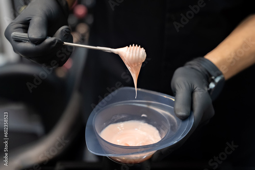 Hairdresser holding bowl with hair dye in beauty salon	