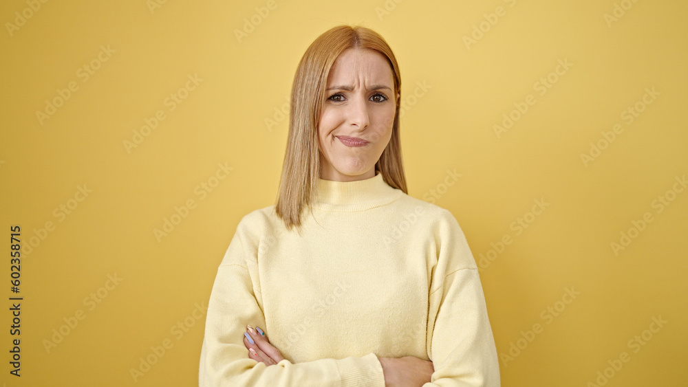 Fototapeta premium Young blonde woman standing with relaxed expression and arms crossed gesture over isolated yellow background