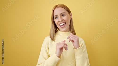 Young blonde woman smiling confident dancing over isolated yellow background
